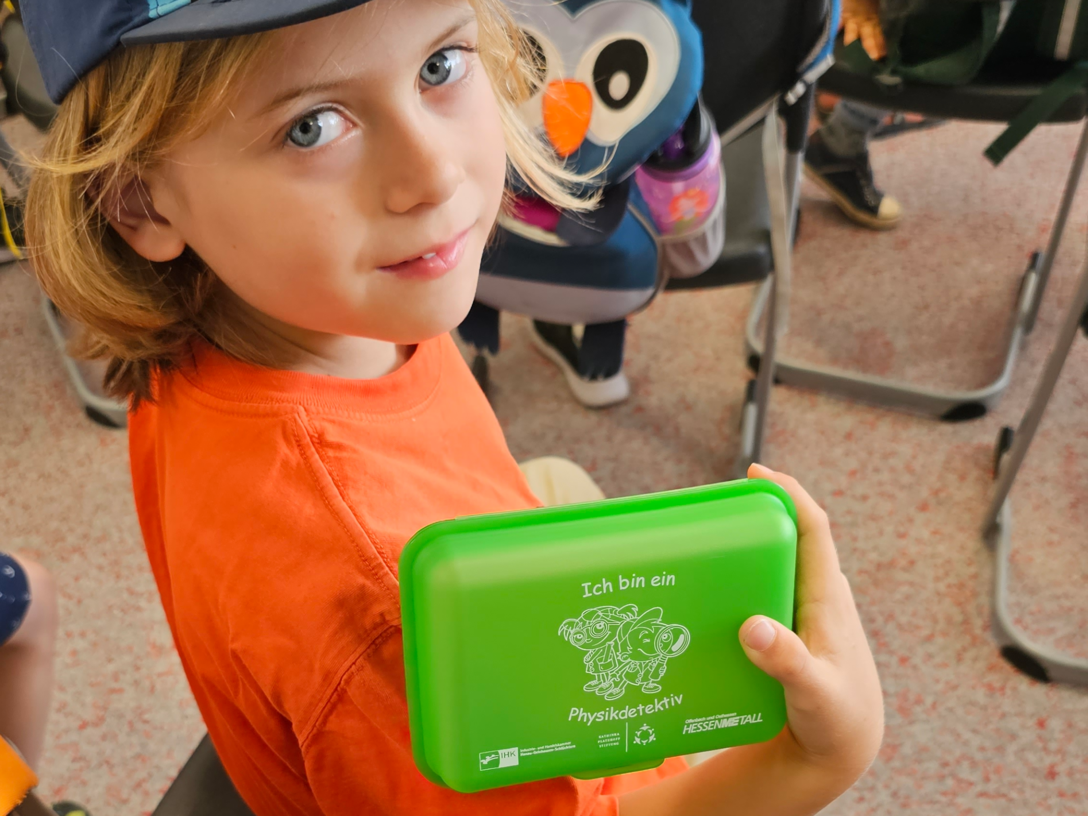 Kindergartenkind mit der „Physikdetektive-Dose", die alle Kinder am Ende der Veranstaltungen bekommen.