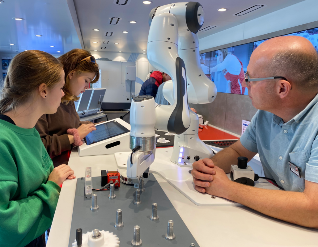 Schülerinnen der Rudolf-Koch-Schule Offenbach mit Truck-Betreuer Marc Buchholtz am programmierbaren Roboterarm.