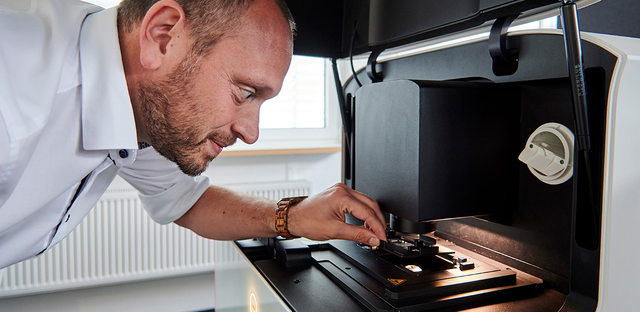 Höchste Präzision: Produktmanager Dr. Patric Pelzer  beim Einlegen einer Probe ins Mikroskop Mica